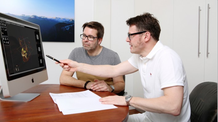 Dr. Meyer zeigt einem Patienten etwas auf einem Bildschirm.