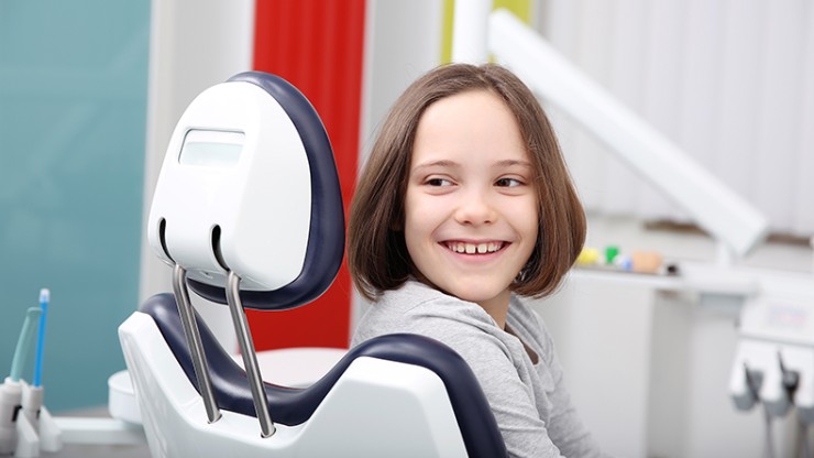 Eine junge Patientin auf dem Zahnarztstuhl.