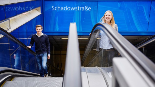 Zwei Menschen fahren Rolltreppe an der U-Bahn-Station Schadowstra&szlig;e.